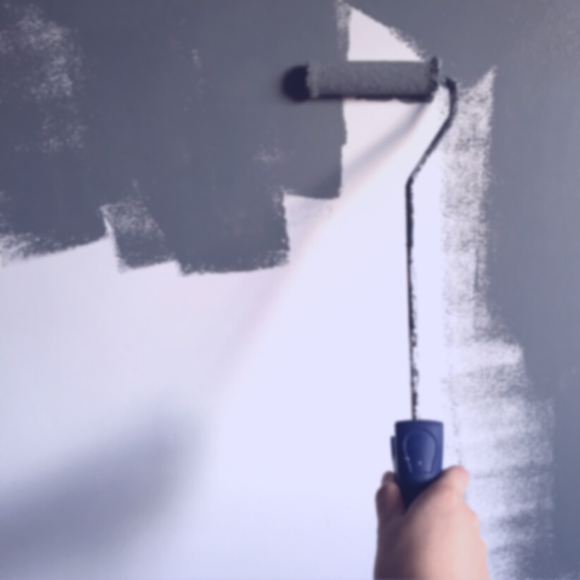 Person Holding Paint Roller While Painting the Wall
